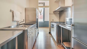 A modern kitchen with stainless steel appliances, a wooden countertop, and a view to the living area.