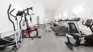 Un gimnasio con cintas de correr, elípticas y equipo de levantamiento de pesas.
