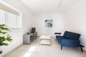 Een moderne woonkamer met een bank, televisie en salontafel.