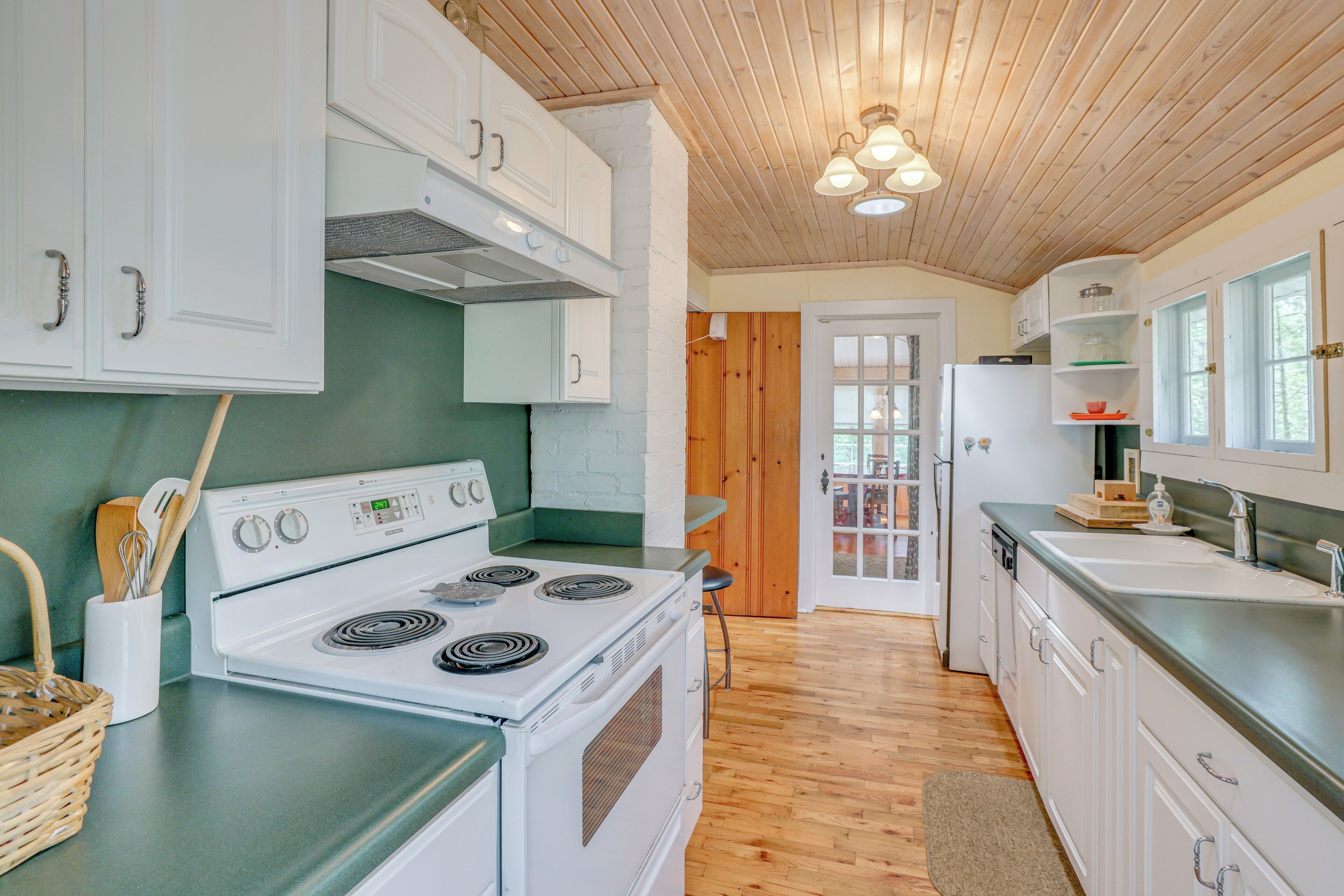 A kitchen with white cabinets, a stove, and a wooden ceiling.