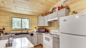 A kitchen with wooden walls, a white refrigerator, a stove, and a microwave. - Gateway to Ouachita National Forest! Cozy Cabin (Glenwood)