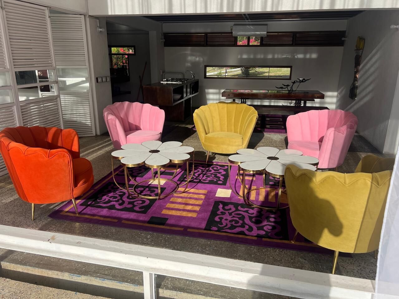 A seating area with chairs and tables, a patterned rug, and a window with a view.