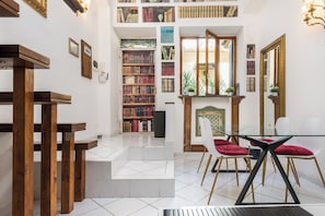 A library with bookshelves, a fireplace, and a dining area with chairs. - Cozy 1-bedroom Loft in gorgeous Roma Trastevere with AC (Roma)