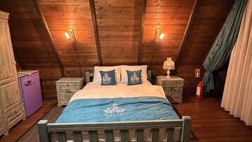 A wooden ceiling with a bed centered in a room, flanked by nightstands and a dresser.