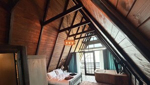 Un dormitorio con techo inclinado, una cama, un aparador, una ventana y un baño con bañera.