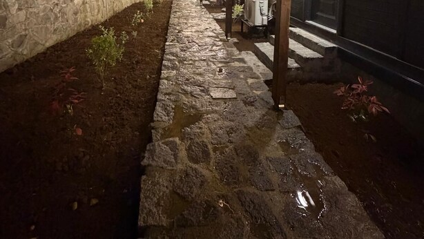 Un camino de piedra que lleva a un edificio con entrada cubierta y una puerta.