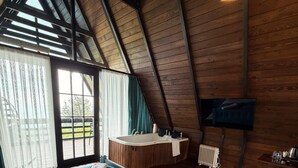 Una habitación con cama, lavamanos, televisión y ventana con cortinas.