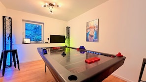 Una habitación con mesa de billar, televisión y obras de arte en las paredes.