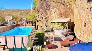 Ein Pool mit Whirlpool, Sitzgelegenheiten im Freien und Blick auf eine steile Klippe.