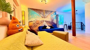 Ein modernes Wohnzimmer mit einem großen Gemälde, einem weichen orangefarbenen Spielzeug und einem blauen Sofa.