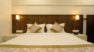 Una habitación de hotel con una cama grande, dos lámparas de noche, un teléfono y un cabecero de madera.
