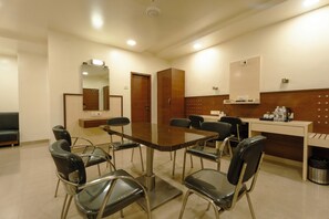 Una sala de conferencias con una mesa rectangular, ocho sillas, un espejo, un armario de madera y un cubo de basura.