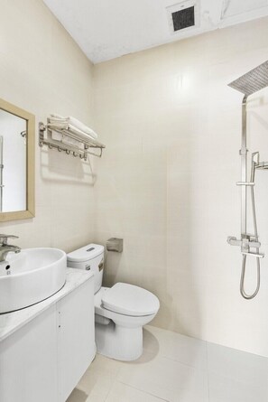 Un baño con lavamanos, inodoro y ducha blancos.