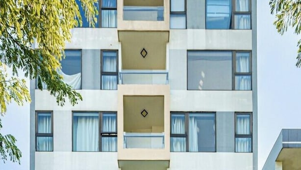 Ett hotell med flera våningar, en modern fasad, en överbyggd entré och en skylt som visar var parkeringsplatsen finns.