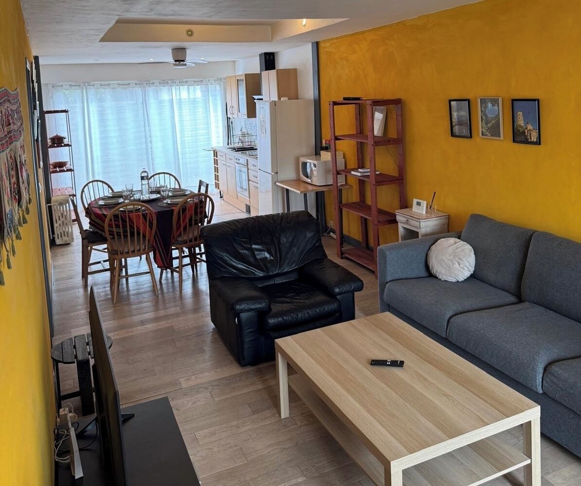 A compact living space with a dining area, a sofa, a coffee table, and a TV.