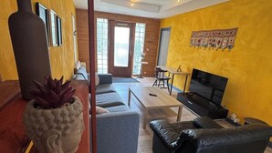 Een woonkamer met een bank, een salontafel, een televisie en een plant.