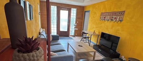 Una sala de estar con un sofá, una mesa de centro, un televisor y una planta.