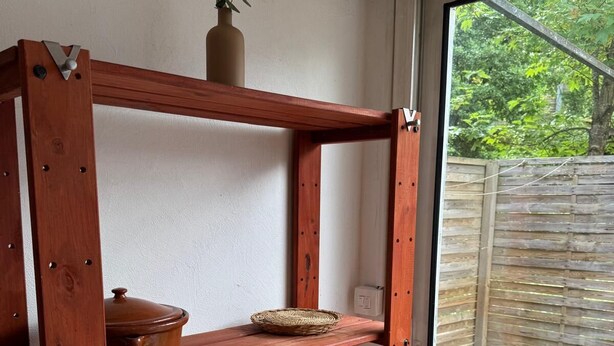 Een houten plankenrek met een keramieken pot en een gevlochten mand.