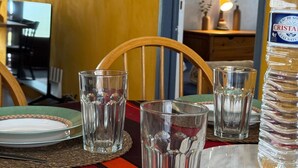 Een eettafel met borden, glazen en een fles Cristal water.