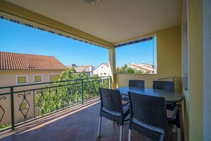 A balcony with a table and chairs, a railing, and a view of buildings and trees. - Vacation apartment for 4 people with balcony and private parking space (Crikvenica)