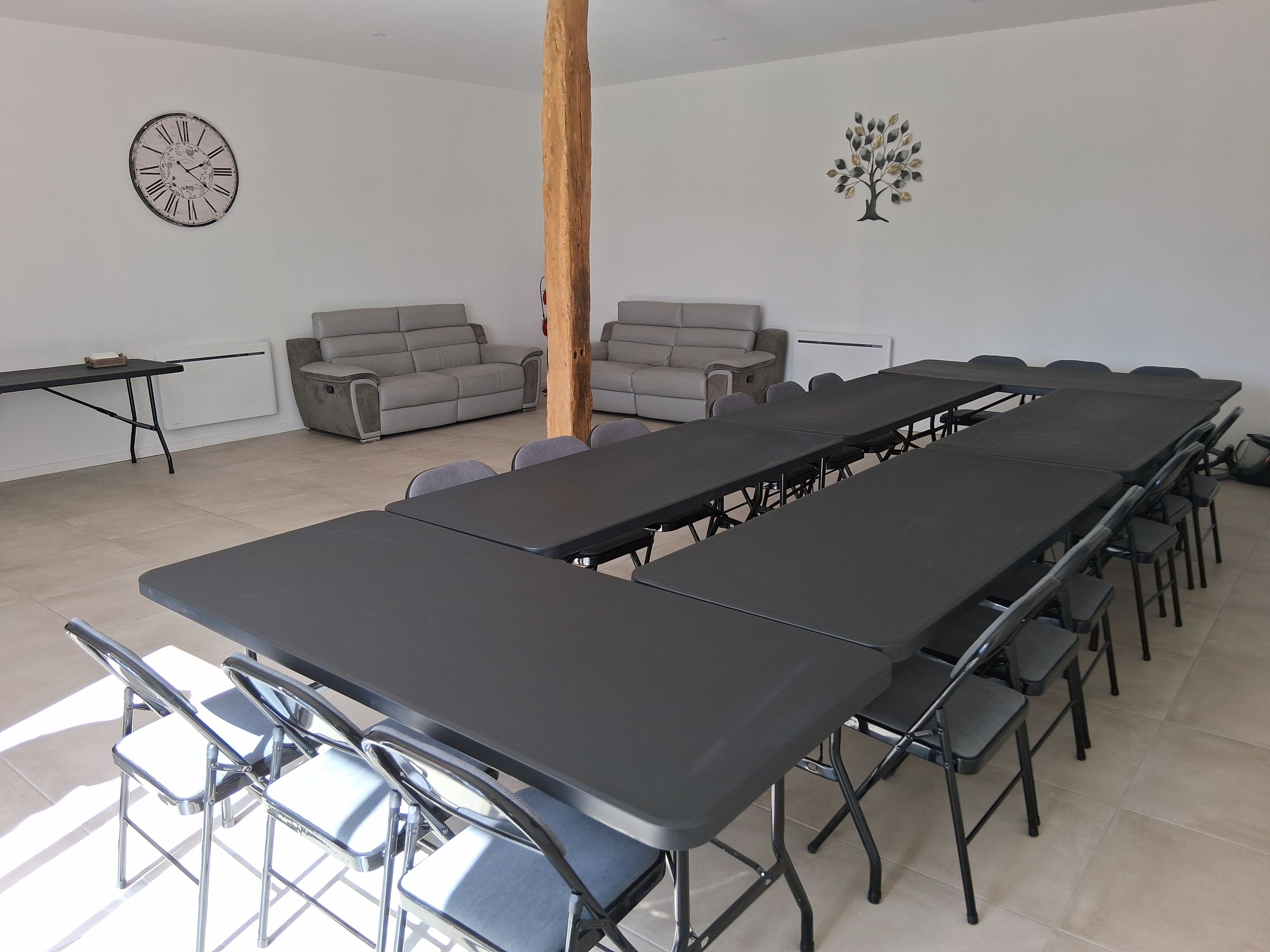 Un salón de conferencias con una larga mesa, sillas, un reloj y un adhesivo con forma de árbol en la pared.