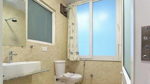 A bathroom with a toilet, sink, and shower. - Oly Emporio Near NDLS (New Delhi)