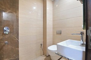 Un baño con pared de mármol, un lavamanos blanco y un inodoro.