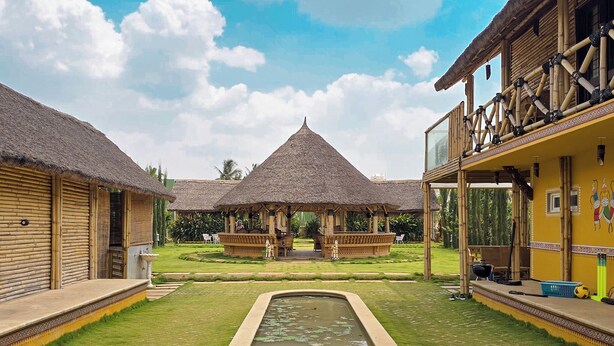 A courtyard with a central pool, thatched-roof structures, and a dining area. - Maharsh Bamboo Stays near Devanahalli (Dyavarahalli)
