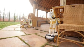 A covered outdoor area with wicker furniture and decorative horse statues. - Maharsh Bamboo Stays near Devanahalli (Dyavarahalli)