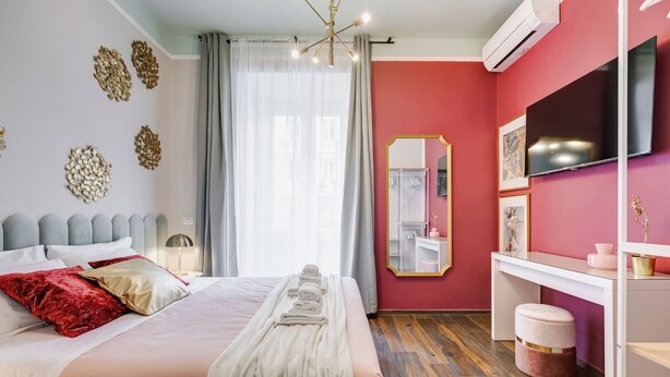 Una habitación de hotel moderna con cama, tocador, espejo y televisor.