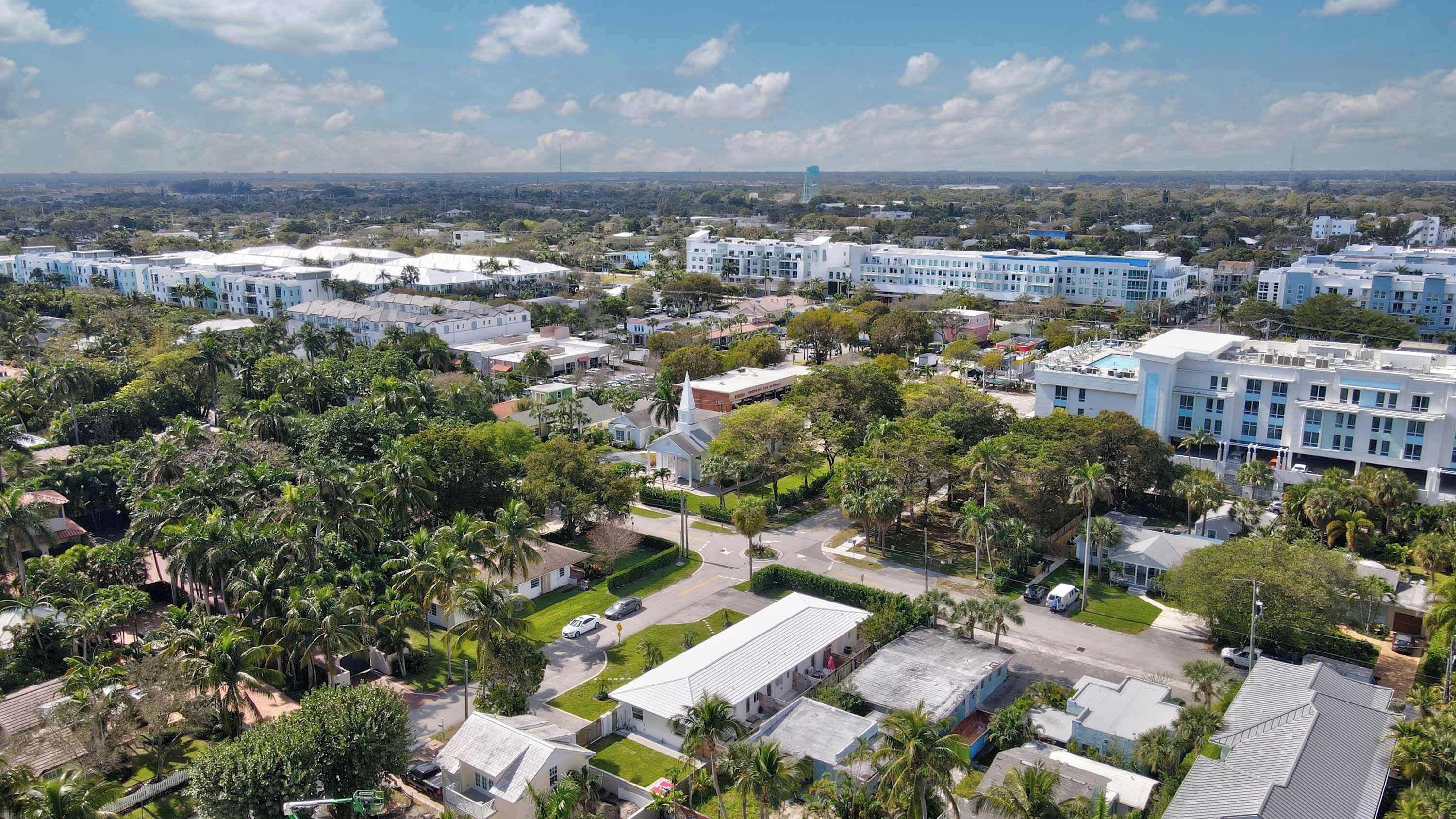 A residential area with multiple-story buildings, a church, and lush greenery.