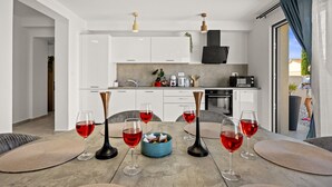 Une cuisine moderne avec des meubles blancs, une table à manger agrémentée de six verres à vin et un bol bleu placé au centre.