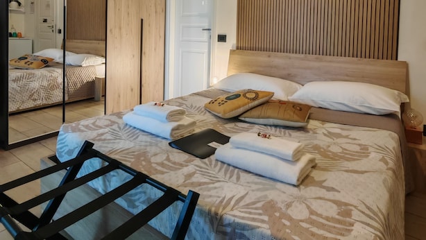 Een moderne slaapkamer met een bed, een houten hoofdbord, een spiegel en een plafondlamp.