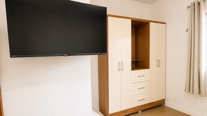 Une pièce dotée d’un téléviseur à écran plat fixé au mur, d’une armoire à plusieurs portes et d’un sol carrelé.