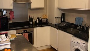 A compact kitchen with a dishwasher, a washing machine, a toaster, and a coffee maker. - Hackney Road Studio Near Shoreditch Markets (London)