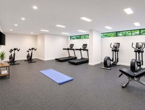 A gym with treadmills, elliptical machines, a bench, and a blue mat. - High-Rise Retreat Near South Bank (Brisbane)