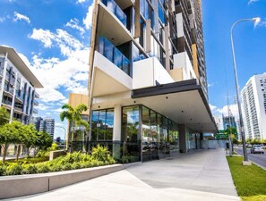 A modern building with a glass facade, a covered entrance, and a landscaped area with plants. - High-Rise Retreat Near South Bank (Brisbane)