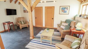Un salon chaleureux avec un plafond en bois, un téléviseur à écran plat, deux canapés, une table basse et un tapis à rayures.