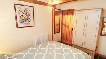 A bedroom with a bed, a radiator, a wooden wardrobe, and a framed picture on the wall.
