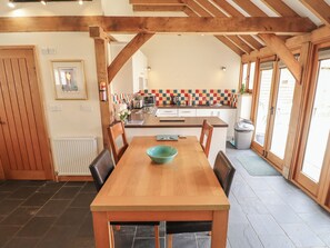 A kitchen with a wooden table, chairs, a tiled backsplash, and a window. - 3b Hideaways (Hunstanton)