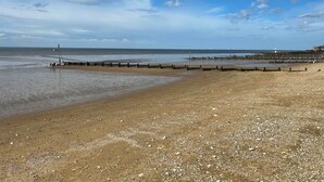 A beach with a wooden jetty, calm water, and a clear sky. - 3b Hideaways (Hunstanton)