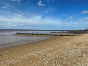 A beach with a wooden jetty, calm water, and a clear sky. - 3b Hideaways (Hunstanton)