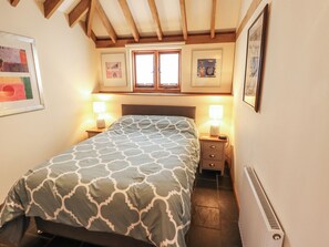 A bedroom with a bed, two bedside tables with lamps, a window, and a radiator. - 3b Hideaways (Hunstanton)