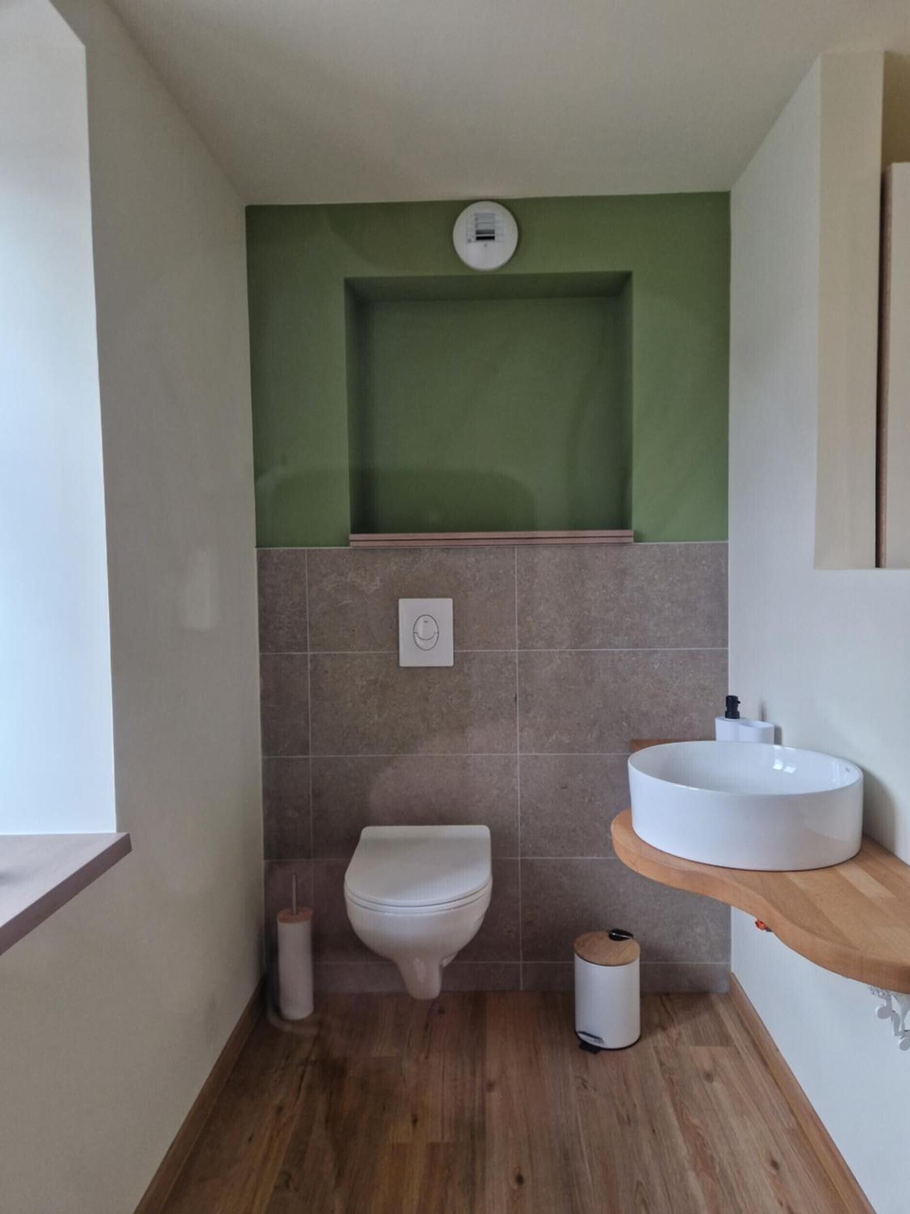 A bathroom with a toilet, a sink, and a toilet paper holder.
