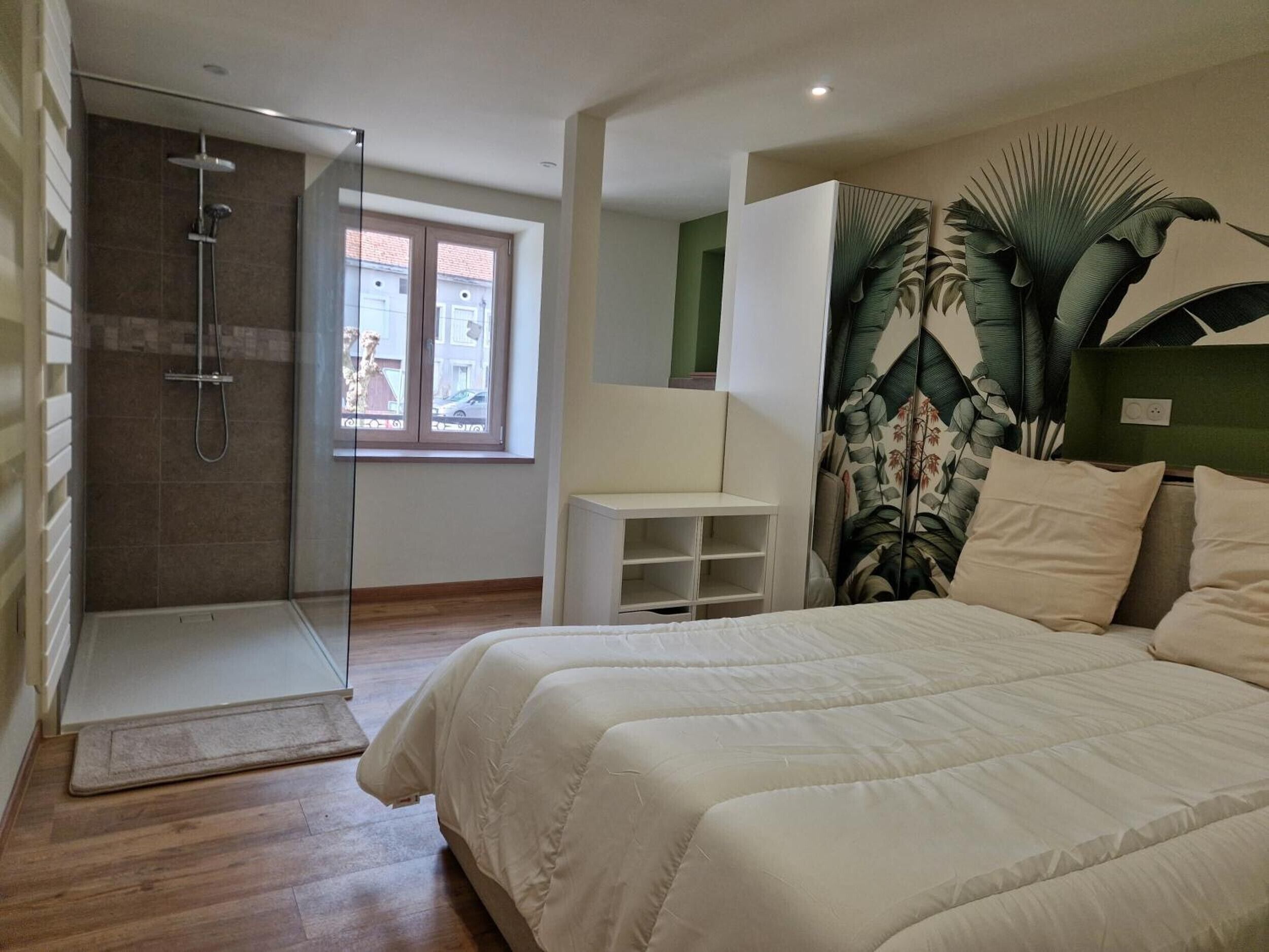 Un dormitorio con cama, ducha, ventana y una planta.
