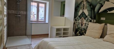 Un dormitorio con cama, ducha, ventana y una planta.