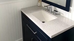 Un baño con un lavamanos blanco, muebles oscuros y dos cuadros en la pared.