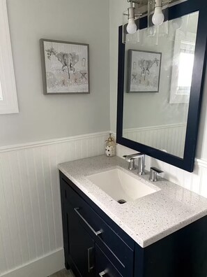 A bathroom with a white sink, dark cabinets, and two framed pictures on the wall. - Less than 2 blocks from Beach w/ 4 beach tags (Seaside Heights)