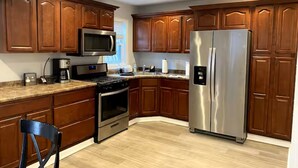 Una cocina con armarios de madera, electrodomésticos de acero inoxidable y encimera de color claro.