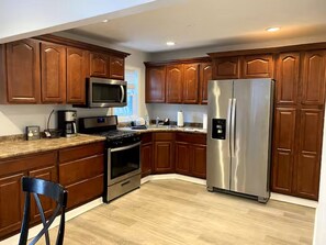 A kitchen with wooden cabinets, stainless steel appliances, and a light-colored countertop. - Less than 2 blocks from Beach w/ 4 beach tags (Seaside Heights)